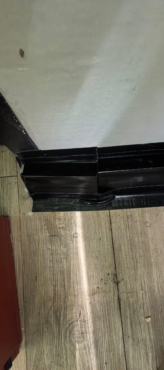 Two bait stations taped along the skirting at the base of a wall